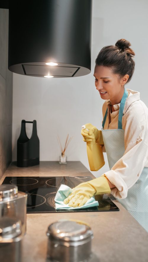 Disinfection. Young dark-haired woman disinfecting the surfaces in the kitchen